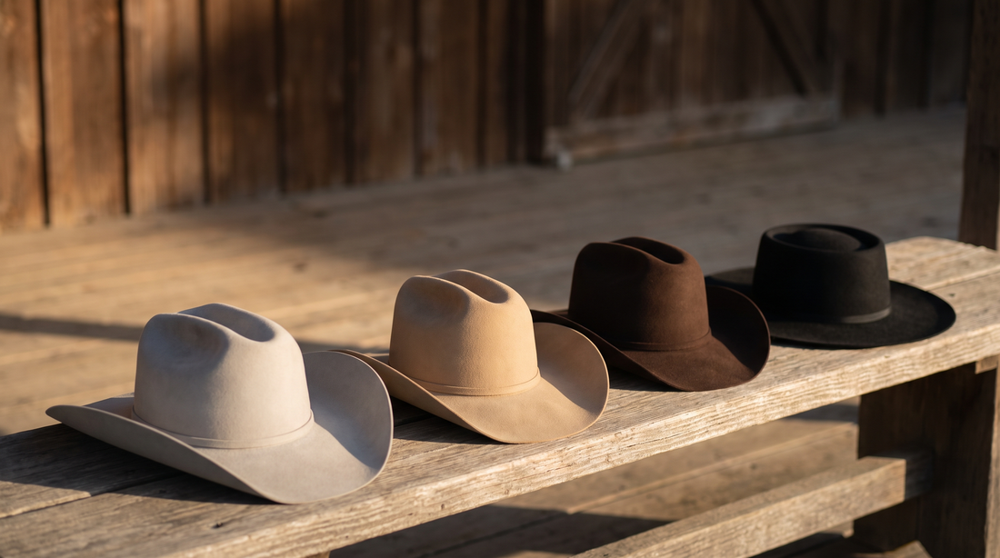 Four felt cowboy hats on a weathered bench in silverbelly, sand, chocolate and black, each with a different crown crease and brim
