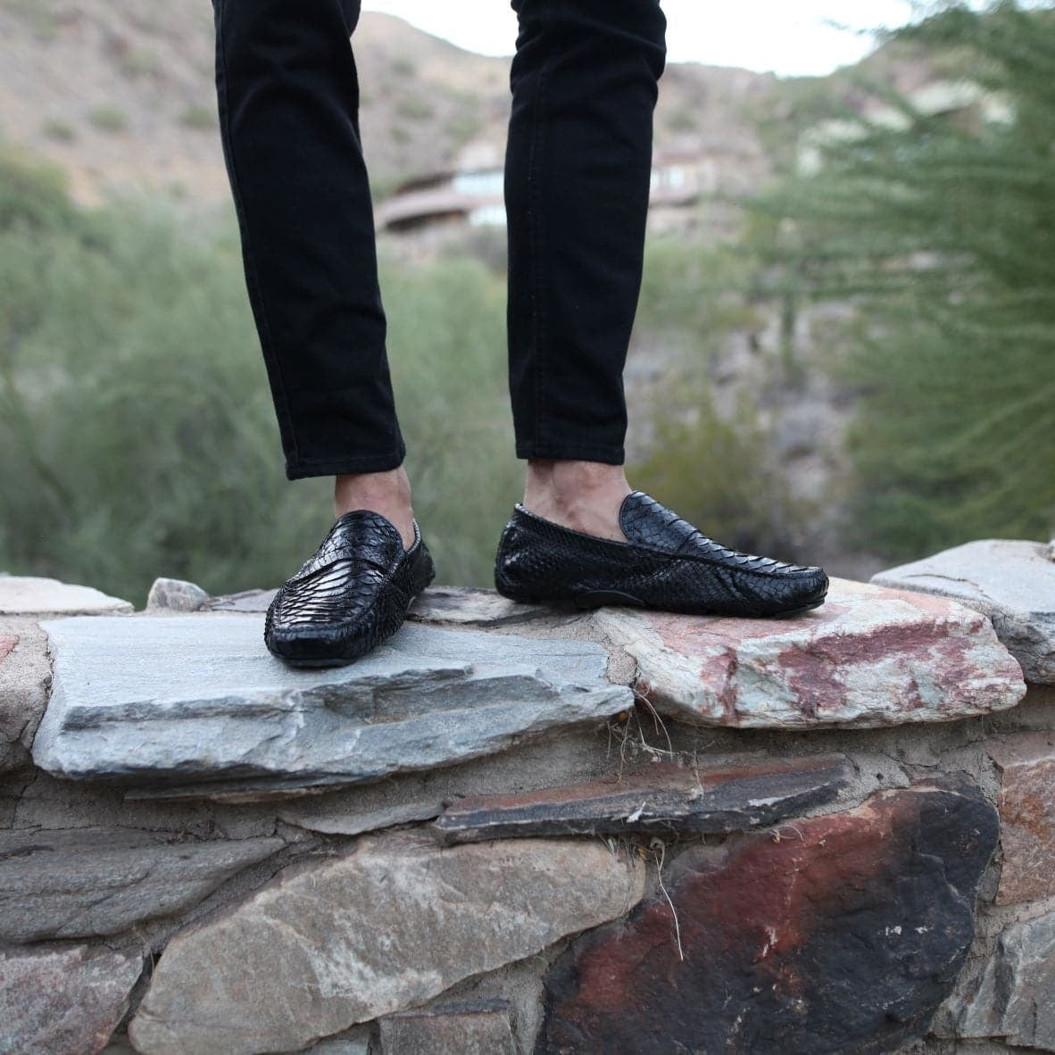 Man standing on a stone ledge wearing The Sprinter loafers with cropped black pants