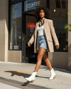 Woman in a blazer and denim shorts walks past a coffee shop in white Trinity boots