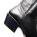 Close-up of the stacked wood-tone heel on The Trinity boot in black with its blue stripe
