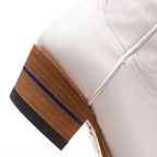 Close-up of the stacked heel on The Trinity boot in white leather with its blue stripe