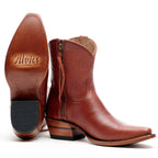The Trinity boots in cognac-brown leather, one upright and one showing its tan sole