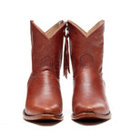 Front-facing pair of The Trinity boots in cognac-brown leather with tasseled zip pulls