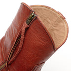 Close-up of the back zipper pull on The Trinity boot in cognac-brown leather