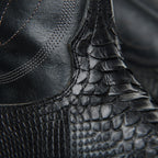 Close-up where smooth black leather shaft meets python vamp on The 6th Street.