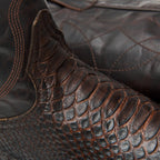 Close-up where brown leather shaft meets python vamp on The 6th Street.