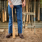 Man holds a baseball bat on gravel wearing The 6th Street brown python boots.