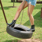 Woman on a tire swing wears black Trinity ankle boots with distressed denim shorts